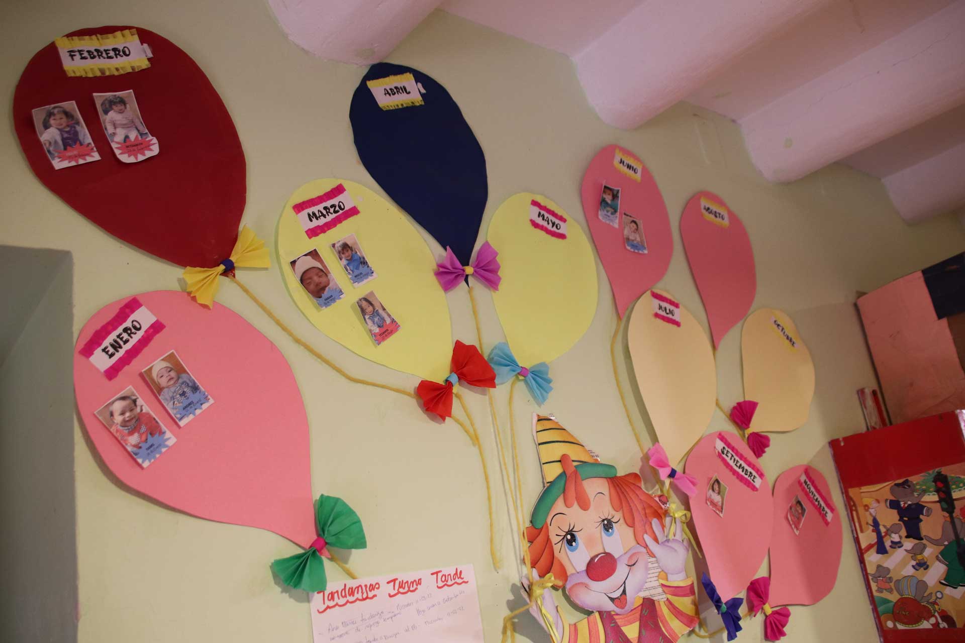 Casa Mantay, Cusco, Peru: Bunter Geburtstagskalender: Papierluftballons mit Monatsnamen & Kinderfotos auf einer gelben Wand