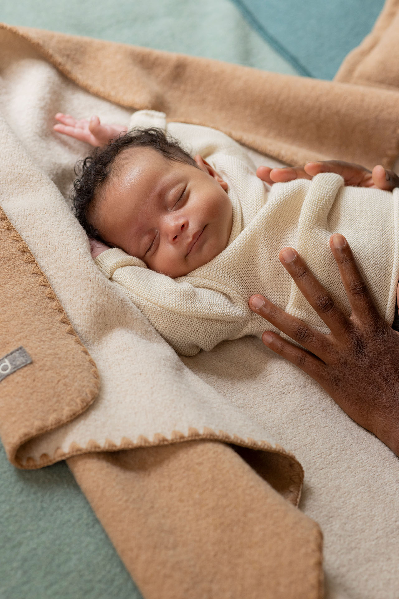 Baby mit hellbraunem Hautton im disana Baby-Pullover, Natur, auf Doubleface-Babydecke in Karamell-Natur schlafend