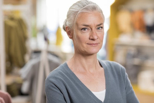 Porträt der disana Produktionsleitung im grauen Pullover, in die Kamera blickend im disana Laden in Holzelfingen