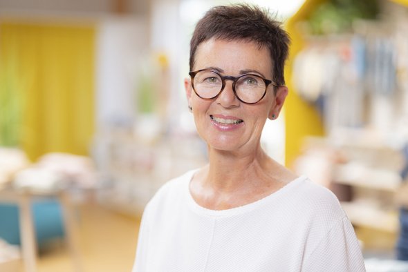 Porträt der disana Mitarbeiterin Meta Bauder im hellen Langarm-Shirt, lächelnd im disana Laden in Holzelfingen