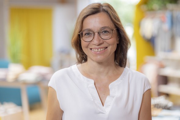 Porträt der disana Mitarbeiterin Elisabeth Courbet im hellen T-Shirt, lächelnd im disana Laden in Holzelfingen