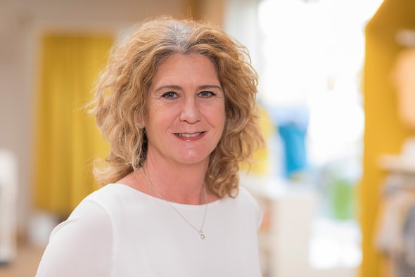 Porträt der disana Mitarbeiterin Silke Schiemann im hellen Langarm-Shirt, lächelnd im disana Laden in Holzelfingen